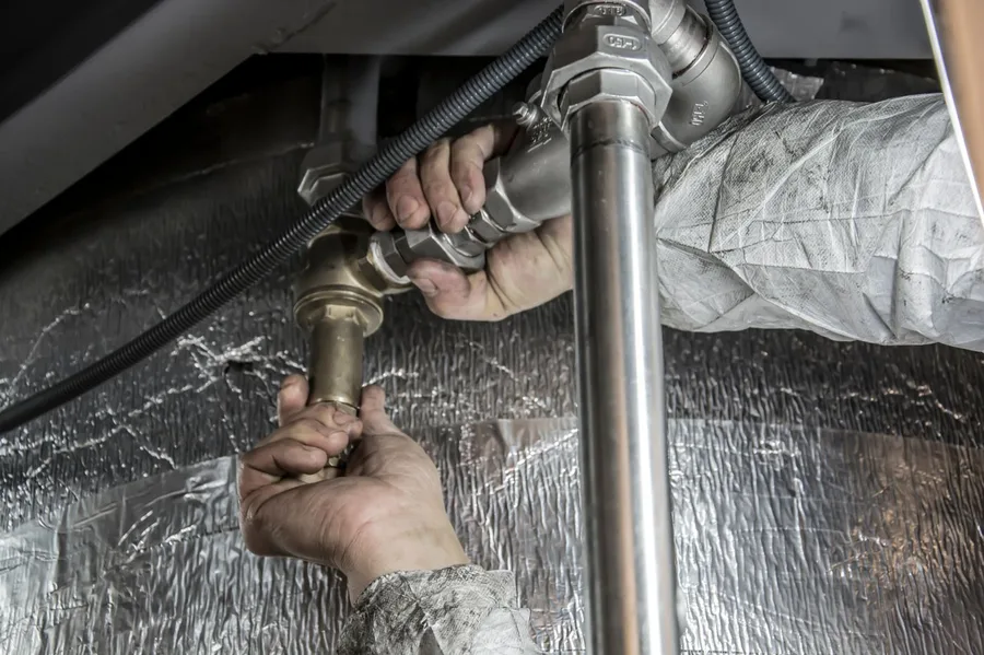 Plombier serrant un raccord de canalisation